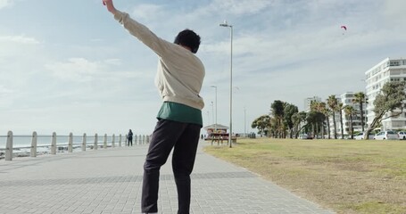 Back, man and dance with headphones at beach for travel, vacation fun and listening to music. Male person, jumping and movement with rhythm, audio and streaming podcast for holiday freedom at seaside - Powered by Adobe