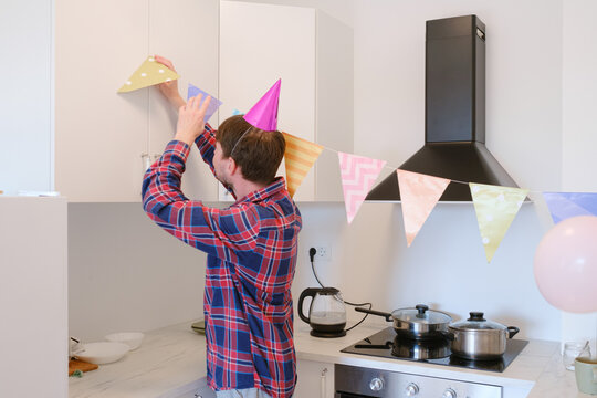 Young man celebrates his birthday at home, surrounded by a cozy and festive setting. He enjoys his special day , creating memories , preparing for the holiday, decorating the room