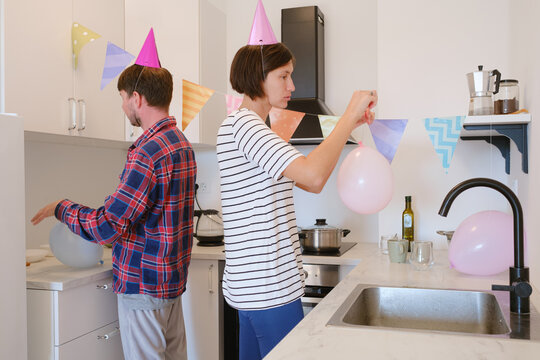 Young couple celebrates cozy birthday at home, enjoying cake and laughter in warm setting. joyful atmosphere, colorful decorations, and shared smiles. preparing for the holiday, decorating the room
