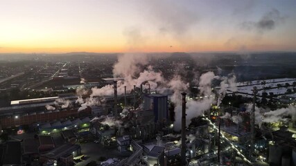 Drone aerial shot of Brazilian paper and pulp industry at sunrise, showing chimneys releasing smoke into the sky, environmental concern