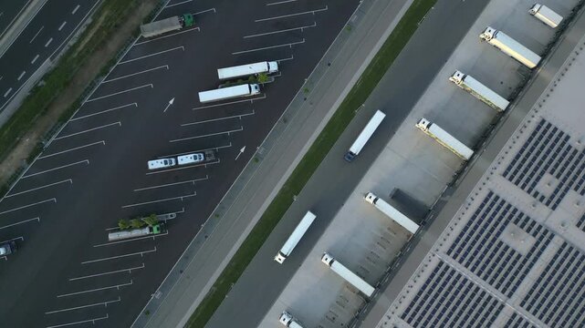 Aerial view of a logistics hub with trucks parked neatly. Captured from above, it shows a busy distribution center near a highway, highlighting efficient freight and cargo management.