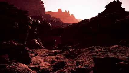 Golden sunlight cascades over stunning reddish rock formations, illuminating the deep canyon. Shadows stretch dramatically across the rugged terrain, highlighting natures artistry at dusk.