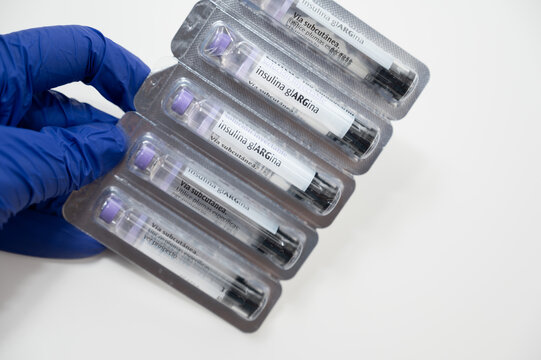 Doctor wearing blue surgical gloves holding insulin glargine pens for diabetes treatment