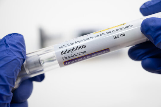 Doctor wearing blue gloves holding a pre filled injection pen of dulaglutide, a weekly injectable medicine for type 2 diabetes