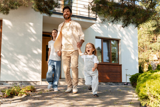 Father leaving home with daughters, holding hands and smiling