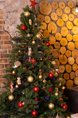 Decorated Christmas tree with red star ornament and glowing lights in cozy rustic interior setting. Winter Holiday season.