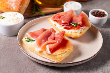 Toast with cream cheese and jamon. Prosciutto crudo open sandwich with rosemary, bread and oil. 