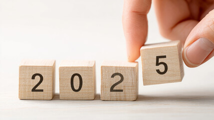 Hand placing wooden block with number five next to blocks reading two zero two to signify year