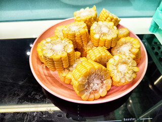 Freshly cut corn pieces displayed on a pink plate, highlighting a vibrant kitchen setting