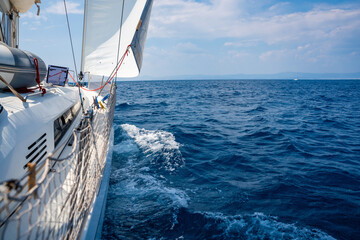 Fototapeta premium Side of a sailing yacht cutting through the sea with full sails near Croatia. Motion, freedom, sailing lifestyle and adventure on the open water.