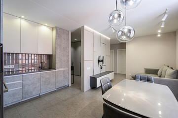 modern interior featuring a kitchen area blending into a living space with a dining table, sofa, and sleek cabinets under warm, ambient lighting