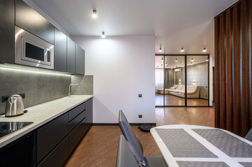 Modern apartment view featuring a sleek kitchen, dining area, and a glimpse into a cozy living room