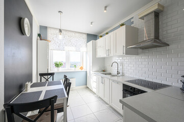 Modern kitchen with dark cabinets, stone backsplash, a stainless steel microwave, and built-in lighting