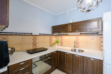 cozy kitchen featuring dark wood cabinets, light countertops, tiled backsplash, and a decorative chandelier