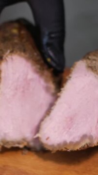 cut meat balyk hands in black latex gloves on a wooden board with a knife cut delicious meat slicing meat plate home cooking smoking