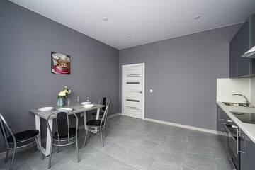 modern, gray-toned kitchen and dining area with a table set for four. The room features minimalist decor and recessed lighting