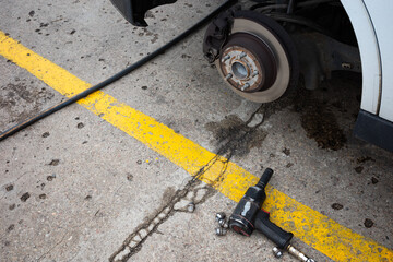 A pneumatic wrench used to change a flat tire on a passenger car. The hub and brake discs are visible after removing the wheel.