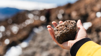Female hiker holds solidified lava stone on Mount Teide, El Teide National Park, Tenerife, Spain.