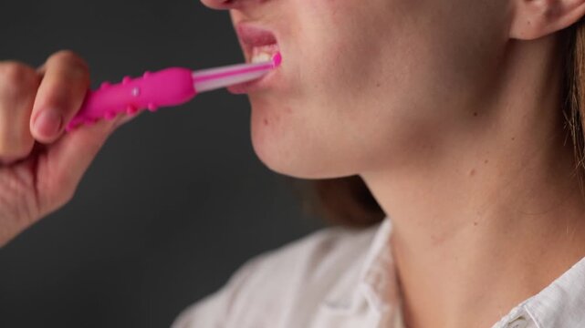 Woman brushing teeth with a colorful toothbrush indoors using good dental hygiene techniques in the evening