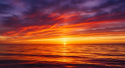 Stunning fiery sunset paints the ocean with vibrant orange and purple hues, creating a breathtaking natural spectacle.