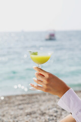 woman holding a cocktail on the beach