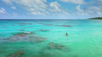 Obraz premium Woman swimming on waves in open sea coral reef. Blue water, tropical exotic island. Outdoor lifestyle travel on summer holiday vacation.