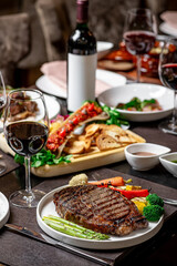 Delicious steak at a fine eatery. A beautifully plated steak with veggies and wine creates an elegant setting for a special evening.