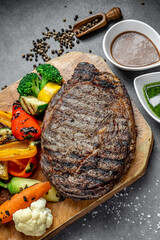 Steak and veggies on board. Juicy grilled steak served with a vibrant mix of roasted vegetables on a rustic wooden board.
