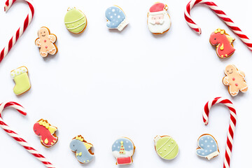 Fototapeta premium Festive composition of Christmas and New Year gingerbread cookies and Christmas Candy Canes on white background, top view. Greeting concept