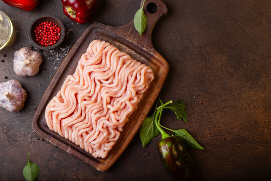 Raw minced meat on cutting board and ingredients. Ground meat with ingredients for cooking on dark background with copy space. Top view
