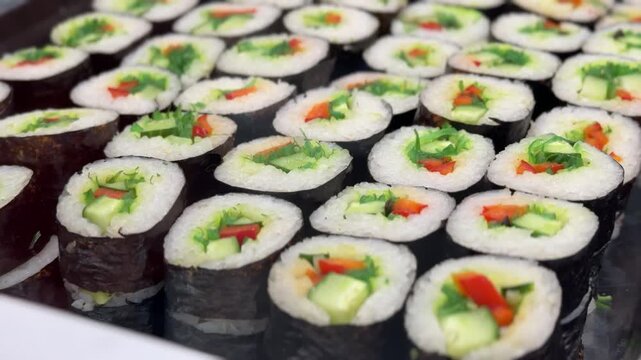 Variety of Freshly Prepared Sushi Rolls Beautifully Arranged on Display for Patrons. Exquisite and vibrant array of sushi rolls brilliantly showcasing various ingredients with artistic presentation.