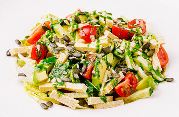 Fresh salad with tomatoes, avocado, and seeds drizzled with dressing