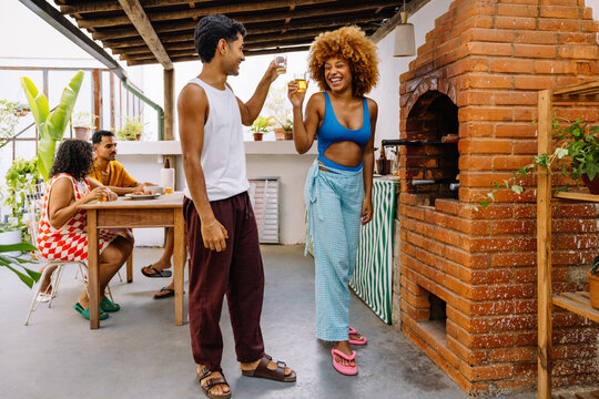Brazilian friends toasting with drinks at backyard barbecue