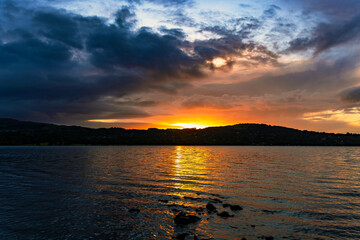 Obraz premium Bright cloudy sunrise reflected in a still lake, Windermere, The Lake District, Cumbria.