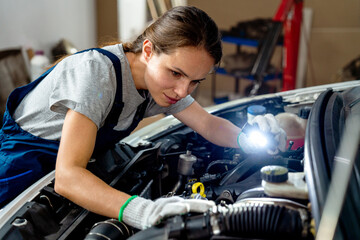 Female auto mechanic working at car repair garage.