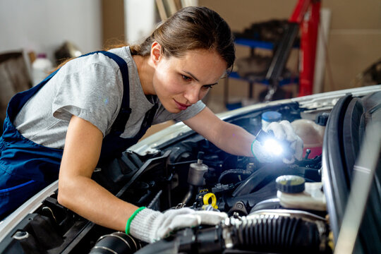 Female auto mechanic working at car repair garage.
