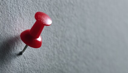 Close-up of a red pushpin on a gray wall