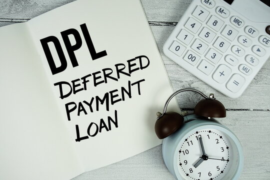 DPL Deferred Payment Loan text on paper notebook page with alarm clock and calculator on wooden background