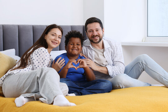 Adoption. Happy parents and their son on bed at home