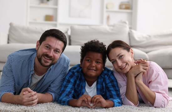 Adoption. Happy parents with their son on floor at home