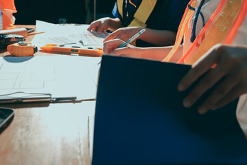 Closeup of team of industrial engineers meeting analyze machinery blueprints consult project on table in manufacturing factory. Working in manufacturing plant or production plant.