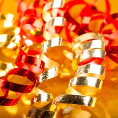 Close-up of red and gold curled ribbons on a yellow surface