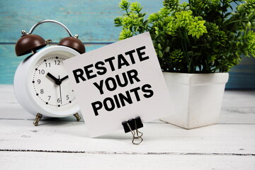 Restate Your Points text written on paper card with alarm clock on wooden background