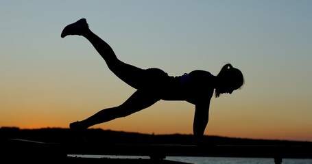 The silhouette of a woman engaging in exercising activities during a beautiful sunset