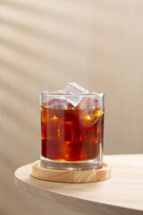 A glass of iced Americano coffee with crystal ice cubes on a wooden table, perfect for coffee lovers seeking a refreshing cold brew moment.