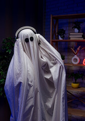 A funny Halloween ghost in a white sheet with black eyes in a dark room with neon lights, dancing...