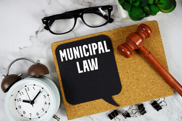Municipal Law text on speech bubble with alarm clock and wooden gavel on marble background