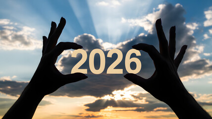 Hands framing the year 2026 against a dramatic sky symbolizing future possibilities and optimism