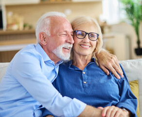 Portrait of a happy senior couple embracing talking at home