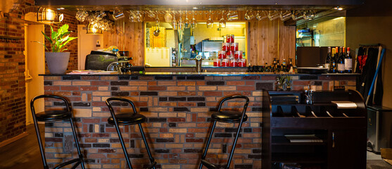Half-lighted hall in a loft style restaurant open kitchen background.